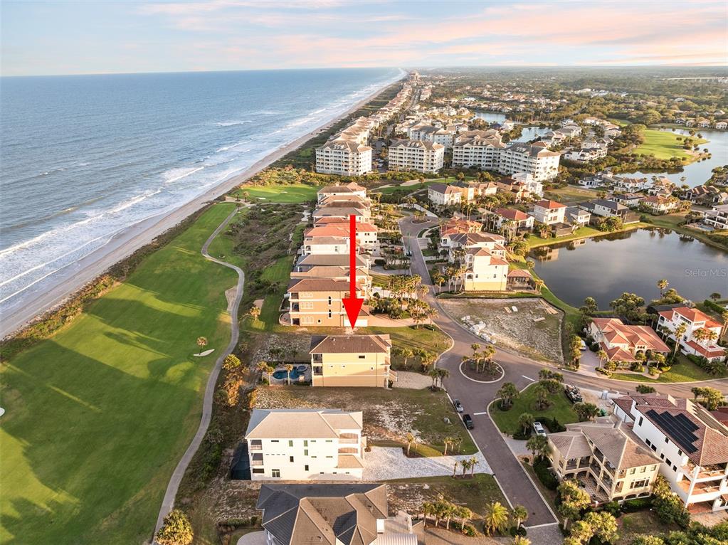 An aerial view shows a coastal neighborhood with houses situated along a beach and golf course — 6 HAMMOCK BEACH COURT, PALM COAST, FL