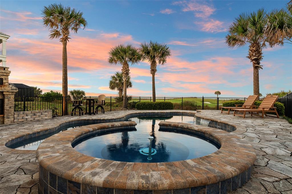 A backyard patio features a circular hot tub, a swimming pool, and palm trees at sunset — 6 HAMMOCK BEACH COURT, PALM COAST, FL