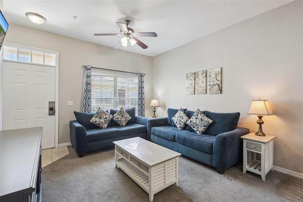 A living room features two blue sofas, a coffee table, and a ceiling fan — 4560 YELLOWGOLD ROAD E UNIT 103, KISSIMMEE, FL