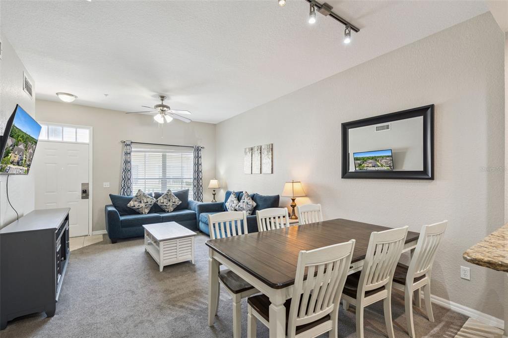 A living and dining area features a blue sectional sofa, a wooden table, and carpeted floors — 4560 YELLOWGOLD ROAD E UNIT 103, KISSIMMEE, FL