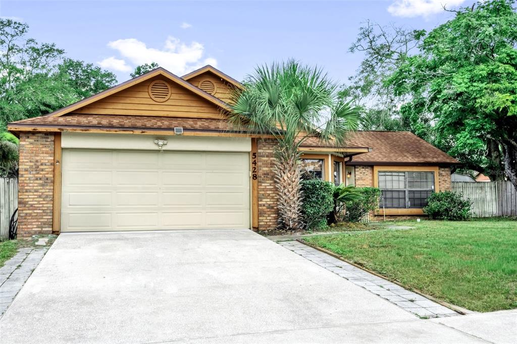 A single-story brick house with a two-car garage, a palm tree, and a concrete driveway — 5428 LIGHTHOUSE ROAD, ORLANDO, FL