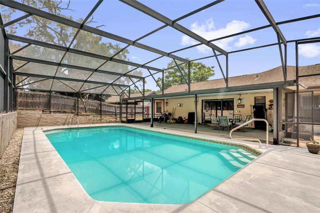 A swimming pool with a screen enclosure sits on a concrete patio beside a house — 5428 LIGHTHOUSE ROAD, ORLANDO, FL