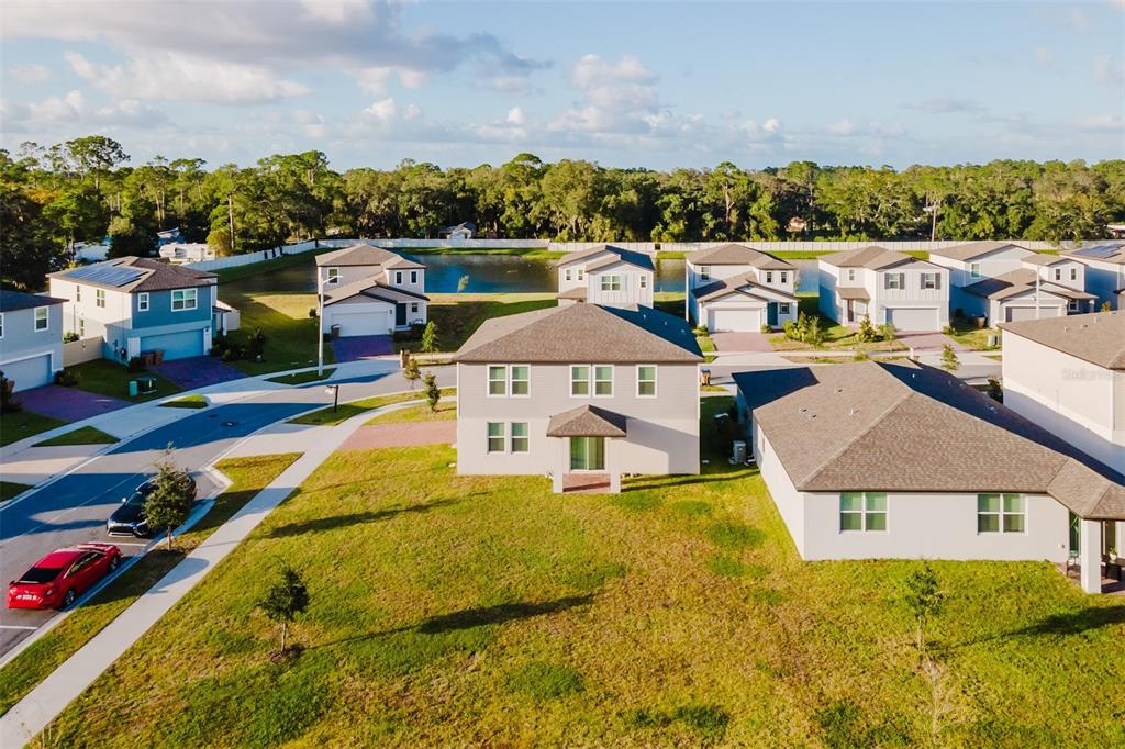 An aerial view shows a two-story suburban house with a large lawn and nearby pond — 5252 SANDERS OAK TRAIL, ST CLOUD, FL