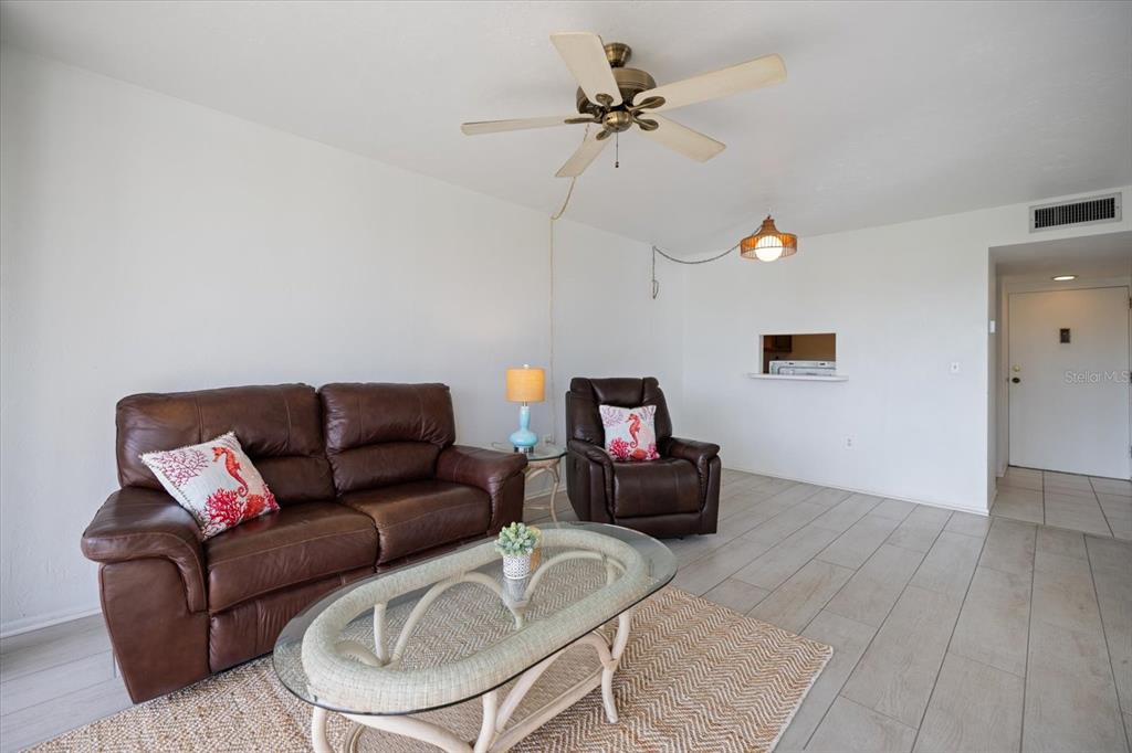 A living room features a brown leather sofa, matching recliner, and a glass-topped coffee table — 618 BIRD BAY DRIVE S UNIT 317, VENICE, FL