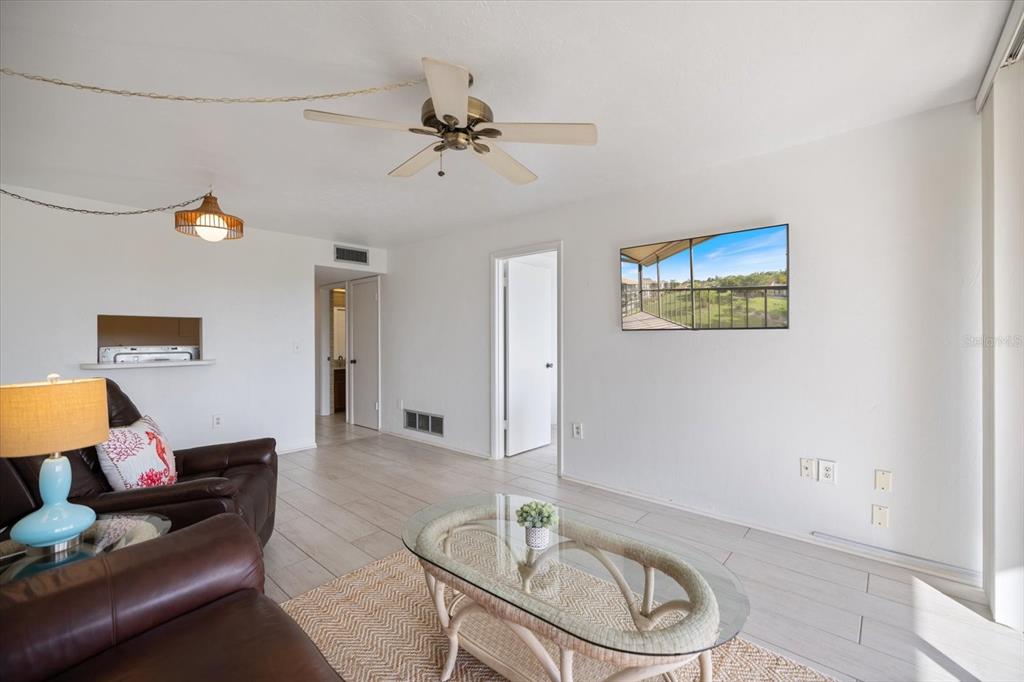 A living room features white walls, tile flooring, a ceiling fan, and a wall-mounted television — 618 BIRD BAY DRIVE S UNIT 317, VENICE, FL
