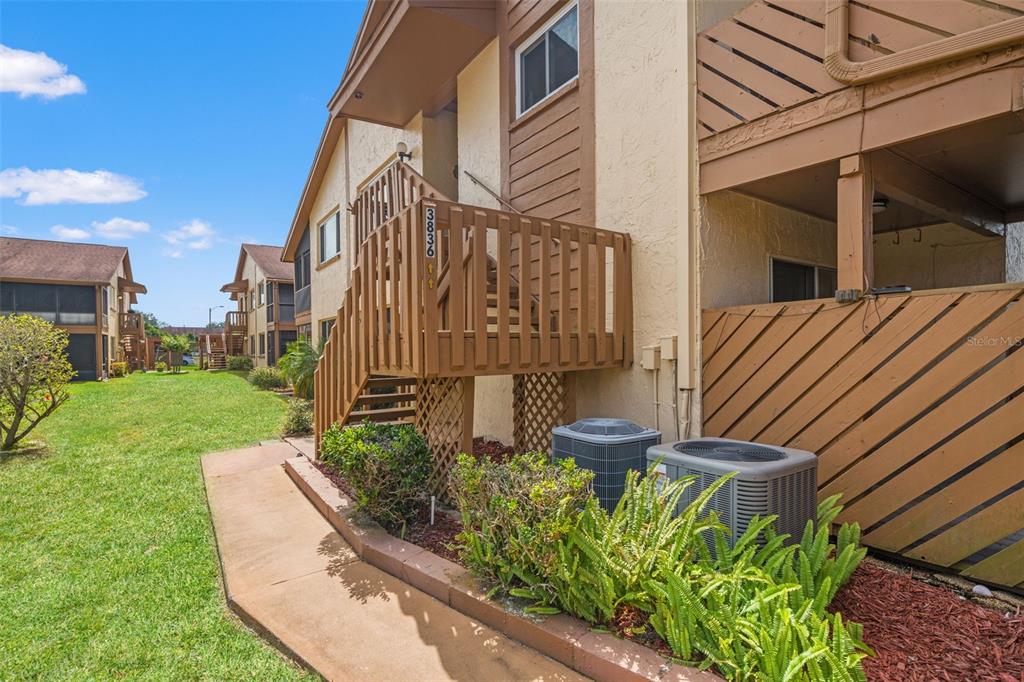 Exterior view of a multi-story apartment building with wooden stairs and two air conditioning units — 3836 LIGHTHOUSE WAY UNIT 3836, NEW PORT RICHEY, FL