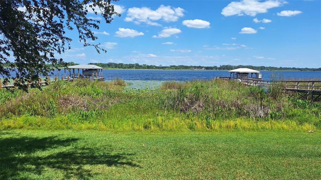 A grassy lawn overlooks a lake with two wooden boat docks and aquatic vegetation — 1803 LAKE VILLA DRIVE, TAVARES, FL
