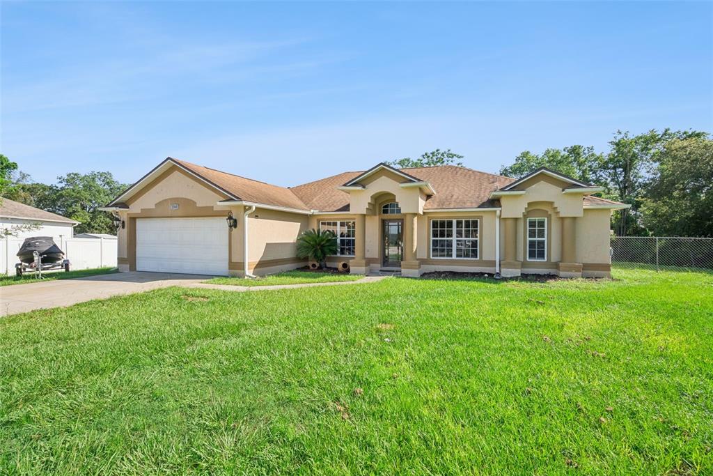 A tan, single-story suburban house features a two-car garage and a front lawn — 1560 GRAY COURT, DELTONA, FL