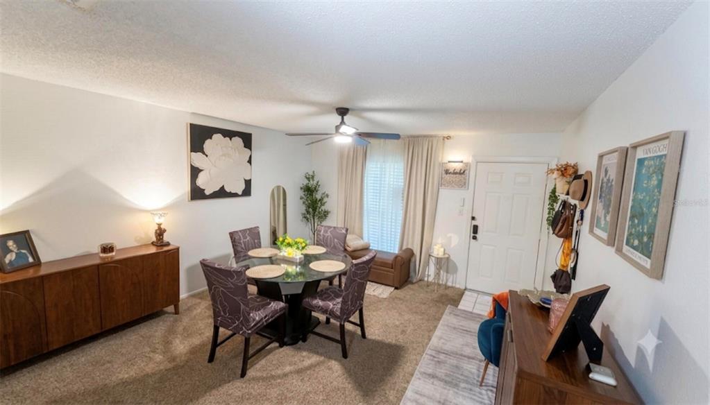 A dining room features a glass table, patterned chairs, a wooden sideboard, and carpeted flooring — 1711 GROVE STREET UNIT 519, MAITLAND, FL