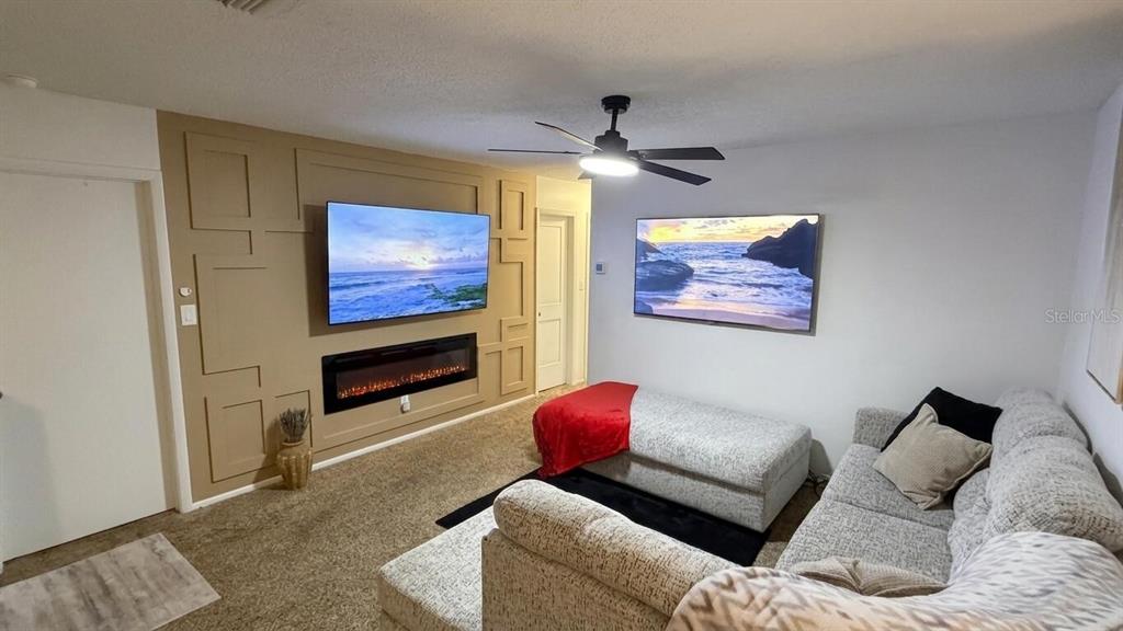 A living room features a paneled accent wall with a fireplace, two televisions, and furniture — 1711 GROVE STREET UNIT 519, MAITLAND, FL