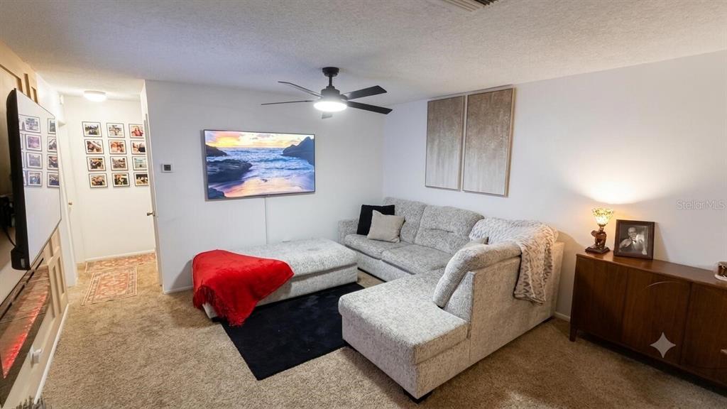 A living room features a sectional sofa, a wall-mounted television, and a ceiling fan — 1711 GROVE STREET UNIT 519, MAITLAND, FL