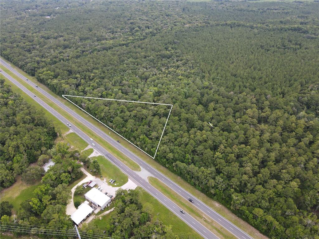 An aerial view shows a triangular plot of wooded land adjacent to a highway — TBD SE HIGHWAY 19, INGLIS, FL