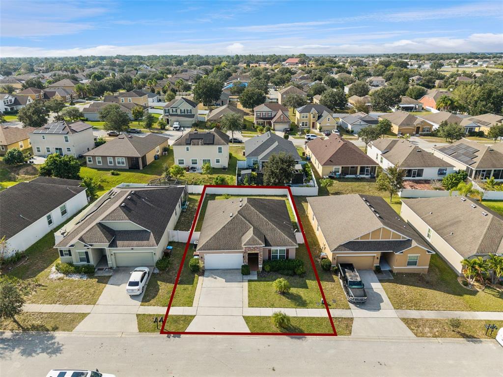An aerial view shows a single-story suburban house with a fenced backyard and driveway — 1038 SUFFRAGETTE CIRCLE, HAINES CITY, FL