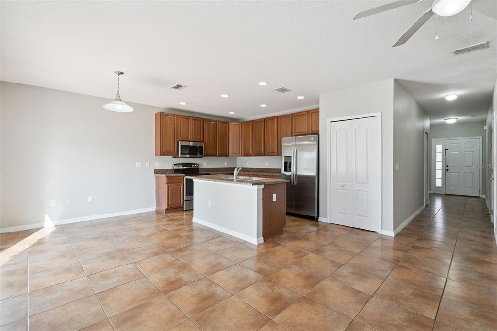 A kitchen with wood cabinets, stainless steel appliances, a center island, and tile flooring — 1038 SUFFRAGETTE CIRCLE, HAINES CITY, FL