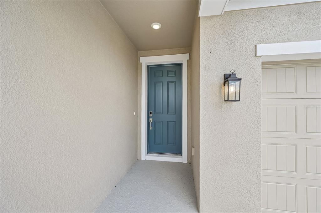 A blue front door is set in a recessed entryway next to a garage door — 5924 FRESH FLORA DRIVE, WIMAUMA, FL