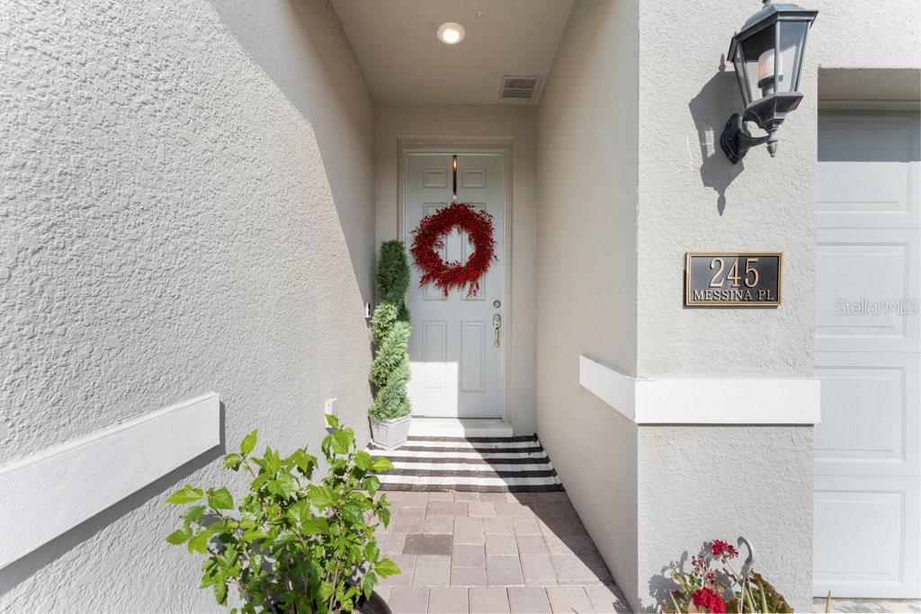 A front entryway features a light-colored door with a red wreath and a paved porch — 245 MESSINA PLACE, HOWEY IN THE HILLS, FL