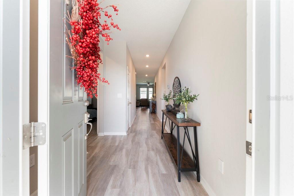 A view from an entryway looking down a long hallway with light wood-look flooring — 245 MESSINA PLACE, HOWEY IN THE HILLS, FL