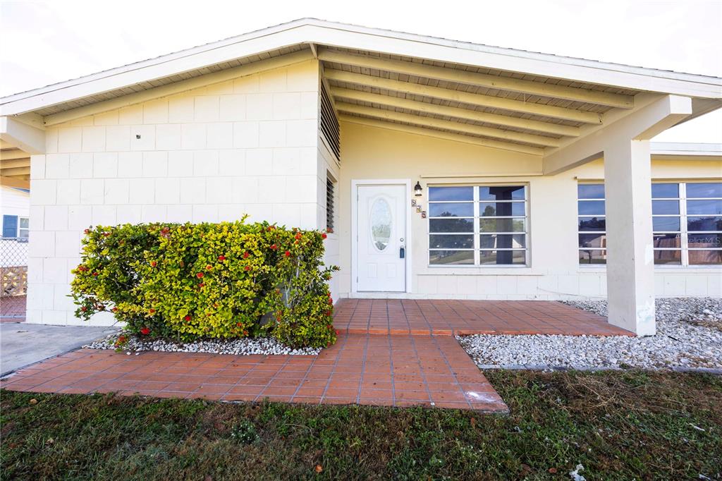 The exterior of a single-story house features a covered porch, white block walls, and landscaping — 275 LAKEVIEW DRIVE, NORTH FORT MYERS, FL
