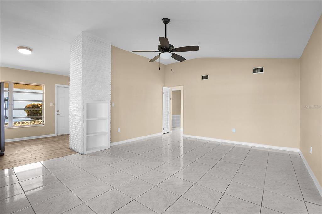 A living room features light-colored tile floors, beige walls, a ceiling fan, and a white fireplace — 275 LAKEVIEW DRIVE, NORTH FORT MYERS, FL