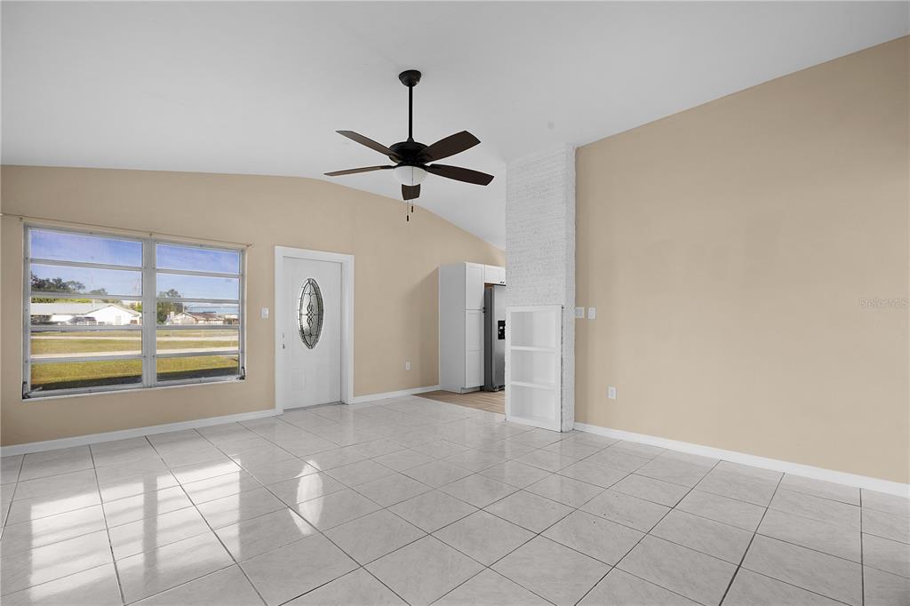 A living room with light-colored tile floors, a vaulted ceiling, and a white brick column — 275 LAKEVIEW DRIVE, NORTH FORT MYERS, FL