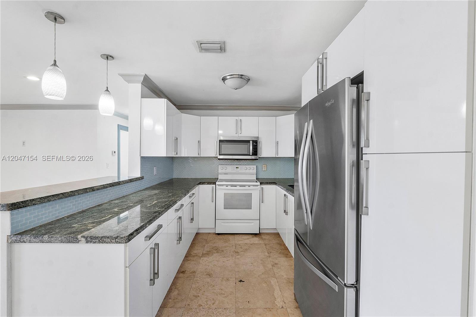 A kitchen features white cabinets, stainless steel appliances, granite countertops, and light blue tile backsplash — 1541 SW 52nd Ave, Plantation FL 33317, PLANTATION, FL