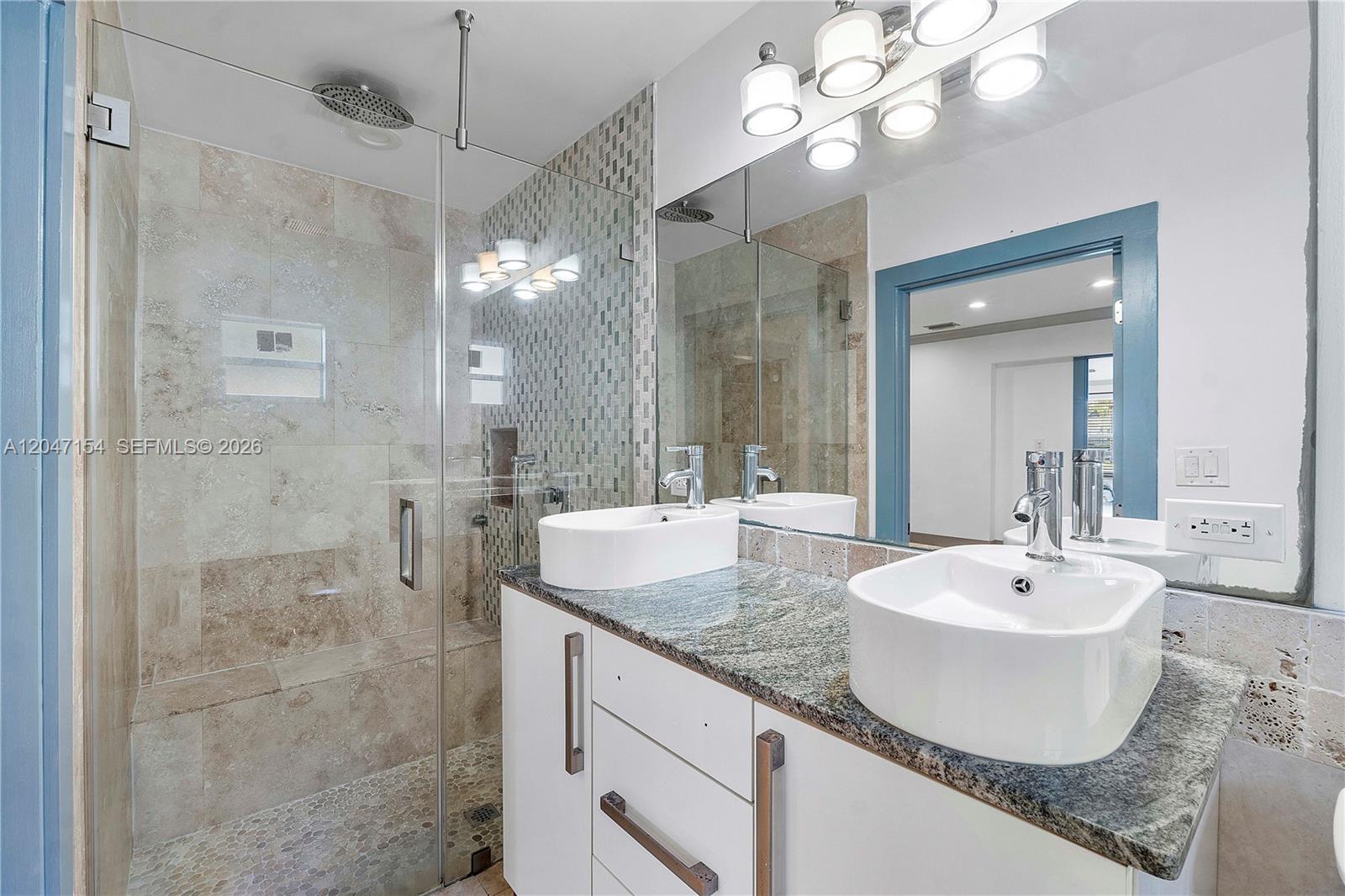 A modern bathroom features a glass-enclosed shower, dual vessel sinks, and granite countertops — 1541 SW 52nd Ave, Plantation FL 33317, PLANTATION, FL