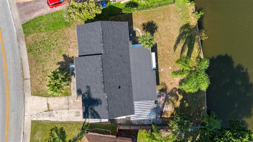An aerial view shows a house with a dark roof, driveway, and yard near water — 3909 SAIL DRIVE, NEW PORT RICHEY, FL