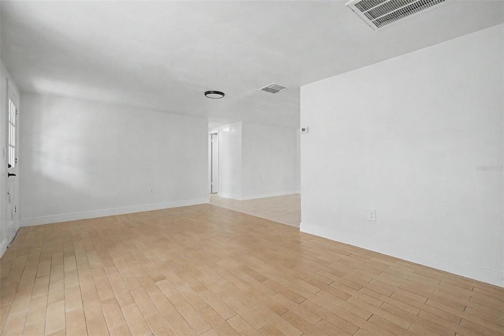 An empty room features light-colored wood-look tile flooring and plain white walls — 3909 SAIL DRIVE, NEW PORT RICHEY, FL
