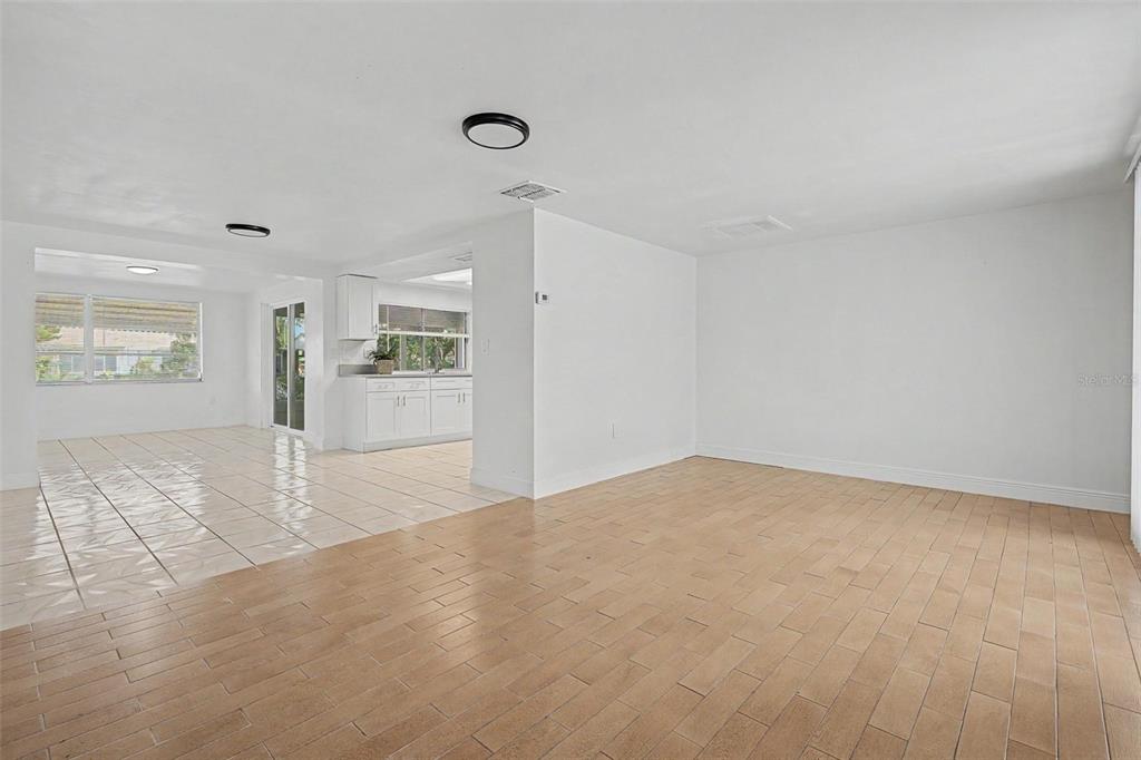 An open-concept living area features light-colored tile flooring and a view into a white kitchen — 3909 SAIL DRIVE, NEW PORT RICHEY, FL