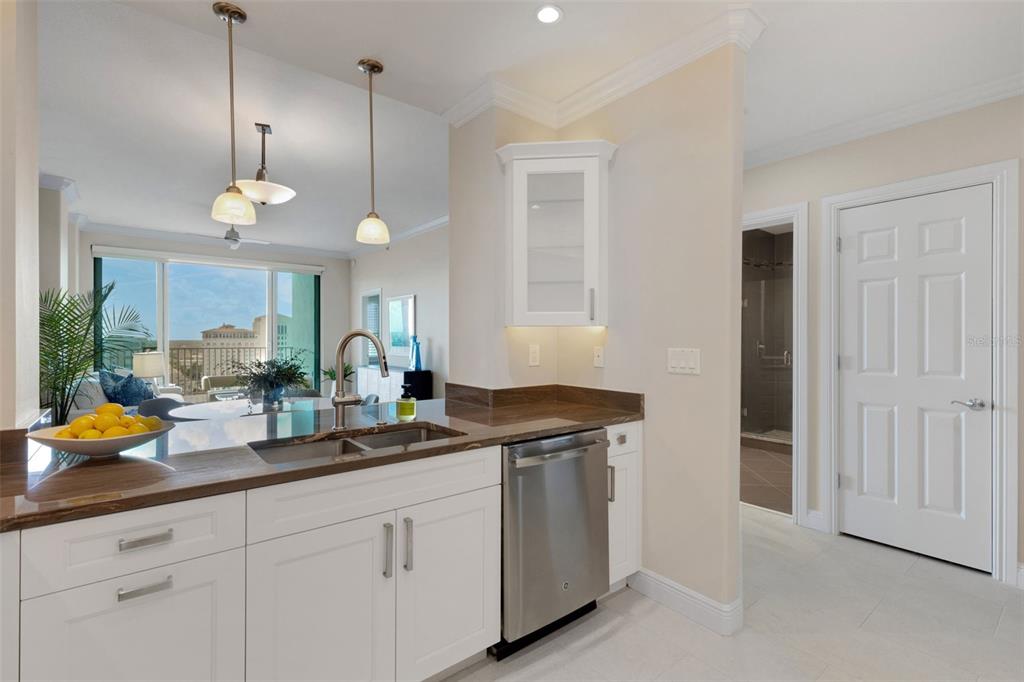 A modern kitchen features white cabinets, stainless steel appliances, and a wood-paneled backsplash — 1771 RINGLING BOULEVARD UNIT 1205, SARASOTA, FL