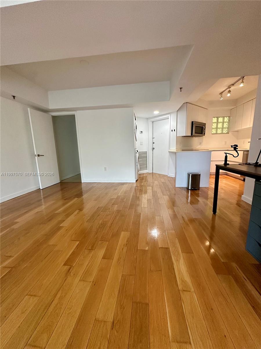 This room features hardwood flooring, a kitchen area, and a white door — 9156 Collins Ave # 202, Surfside FL 33154, SURFSIDE, FL