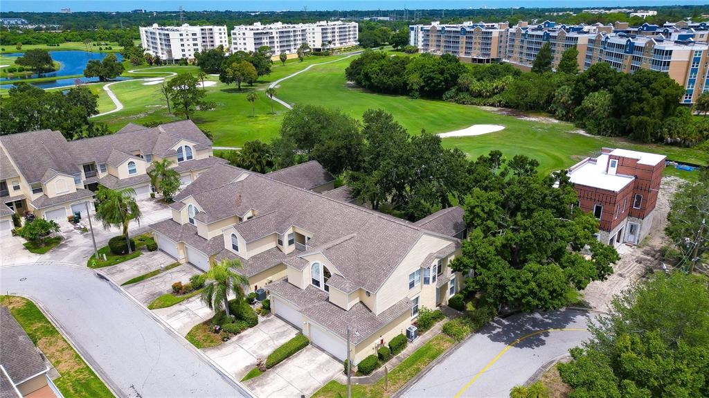 An aerial view shows multi-story townhomes with attached garages situated next to a golf course — 1050 STARKEY ROAD UNIT 2105, LARGO, FL