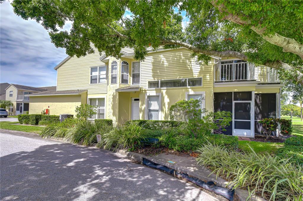 A two-story yellow townhouse with a screened-in porch and a second-floor balcony — 1050 STARKEY ROAD UNIT 2105, LARGO, FL