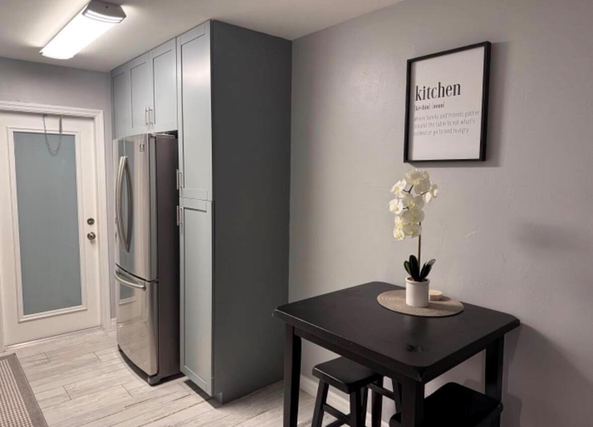 A kitchen features a stainless steel refrigerator, blue cabinetry, a small black table, and wall art — 136 Akron Street # B2, FL 33461, FL