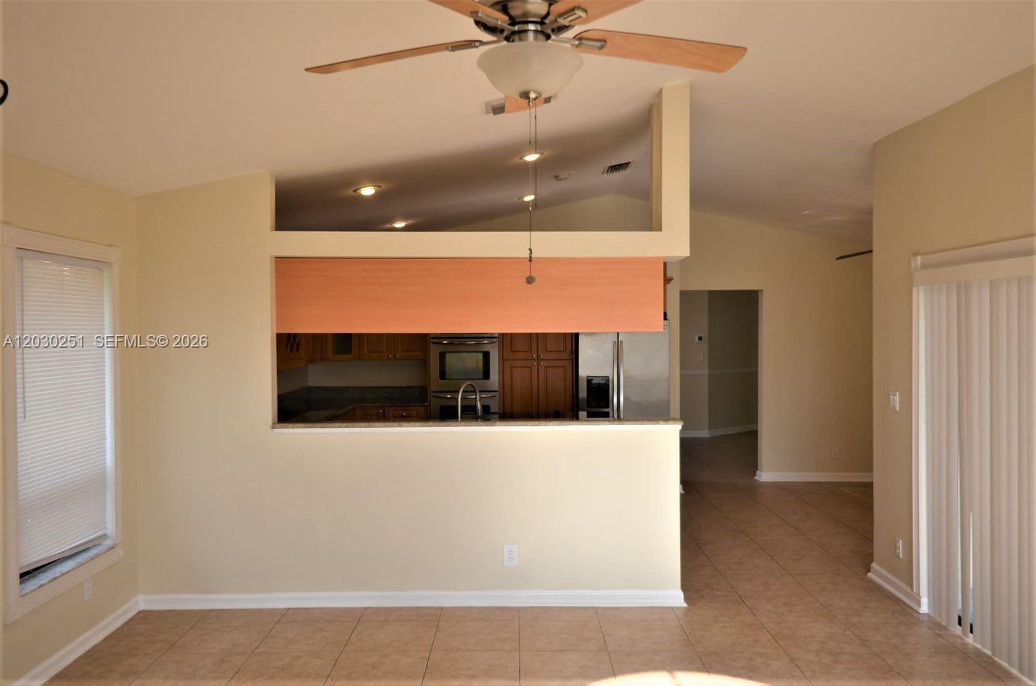 A kitchen with wood cabinets is visible through a pass-through opening in a living area — CORAL SPRINGS, FL