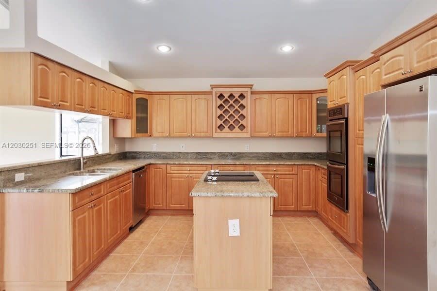 A kitchen features light wood cabinets, granite countertops, a central island, and stainless steel appliances — CORAL SPRINGS, FL