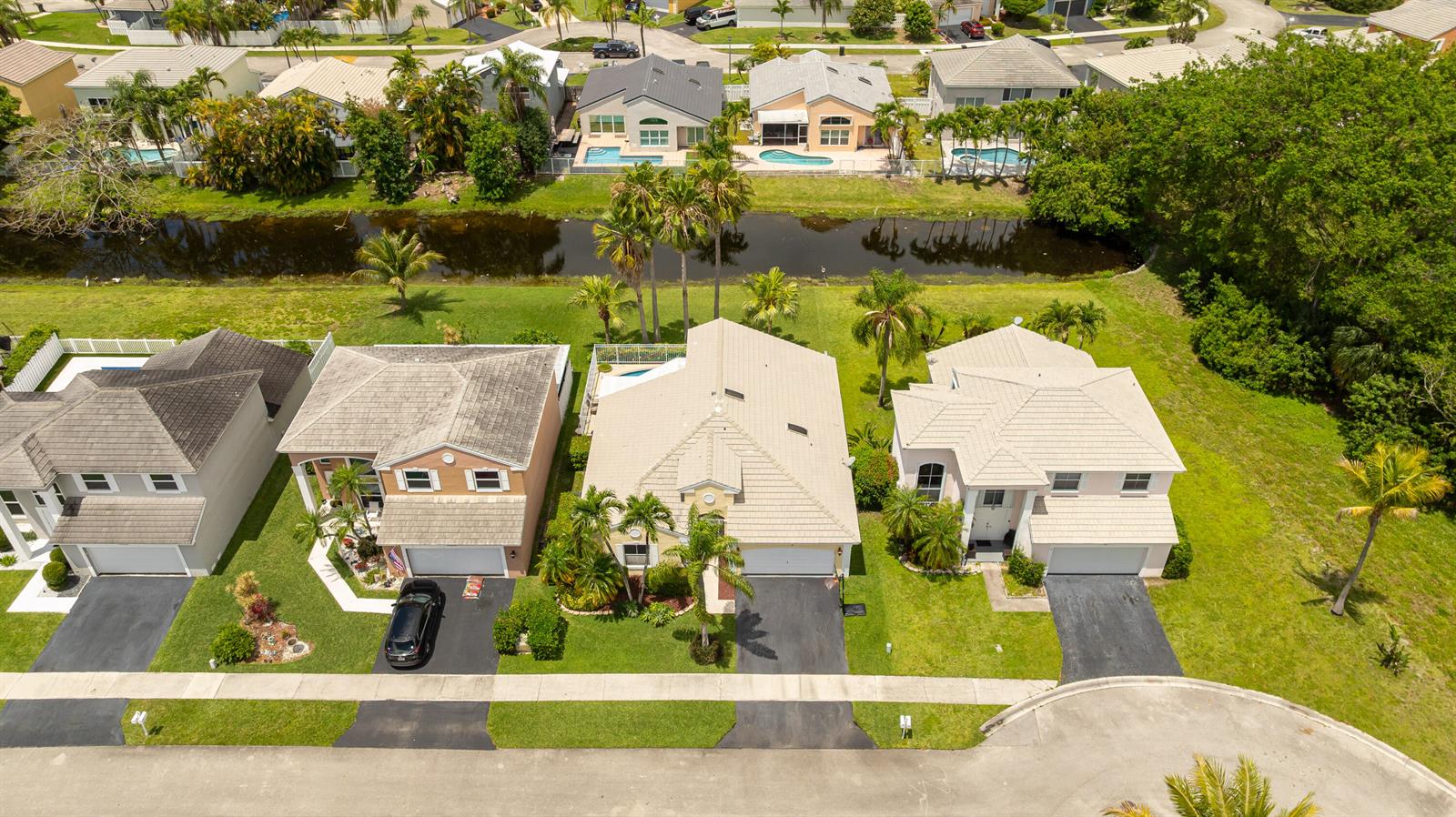 An aerial view shows three suburban houses with tiled roofs and driveways facing a street — 5535 NW 54th Circle, Coconut Creek FL 33073, COCONUT CREEK, FL