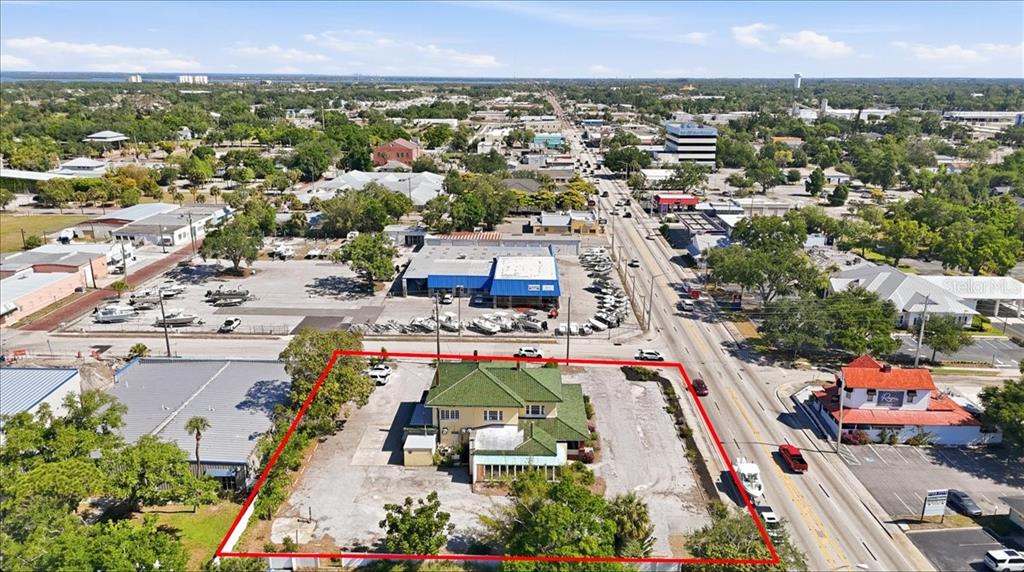 An aerial view shows a yellow house with a green roof on a paved lot — 337 8TH AVENUE W, PALMETTO, FL