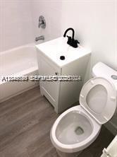A small bathroom features a white vanity with a black faucet, toilet, and bathtub — 30 S Shore Dr # 6, Miami Beach FL 33141, MIAMI BEACH, FL