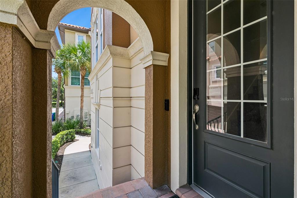 A view from a covered entryway looking out toward a sidewalk and palm trees — 316 TRIESTE LOOP, LAKE MARY, FL