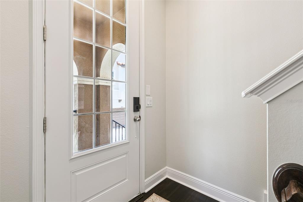 A white front door with glass panes opens into an entryway with dark wood flooring — 316 TRIESTE LOOP, LAKE MARY, FL