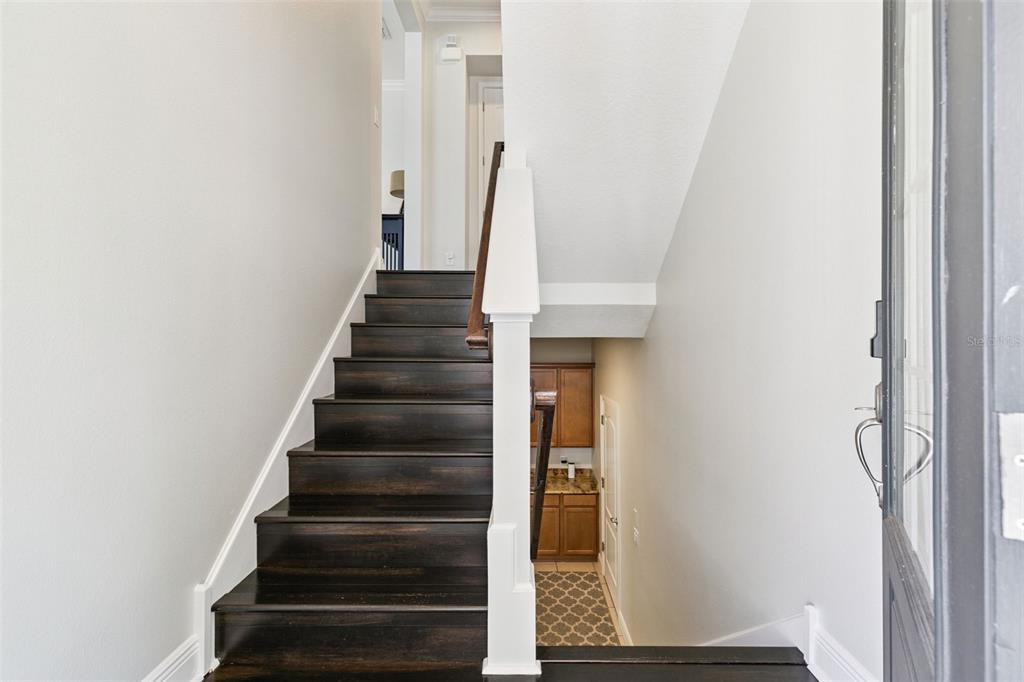 A staircase with dark wood treads and a white railing leads to an upper level — 316 TRIESTE LOOP, LAKE MARY, FL