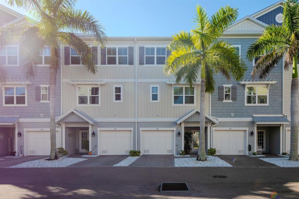 A row of multi-story townhomes with attached garages, palm trees, and light-colored siding — 196 HAVEN BEACH DRIVE, INDIAN ROCKS BEACH, FL