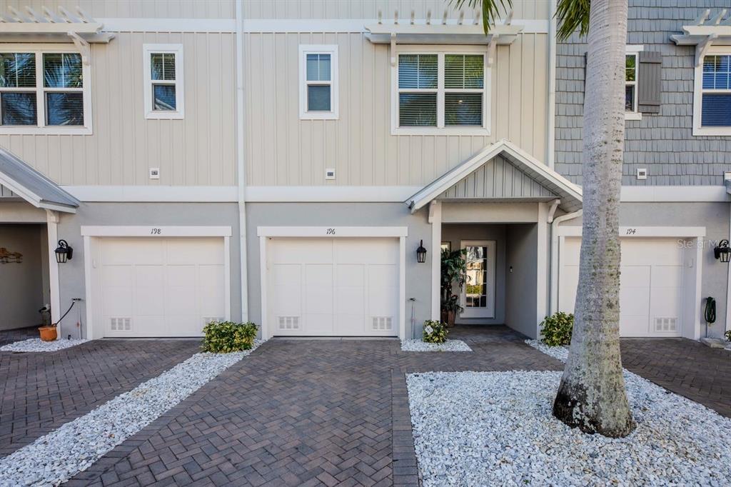 A row of townhouses with white garage doors, light-colored siding, and a paved driveway — 196 HAVEN BEACH DRIVE, INDIAN ROCKS BEACH, FL