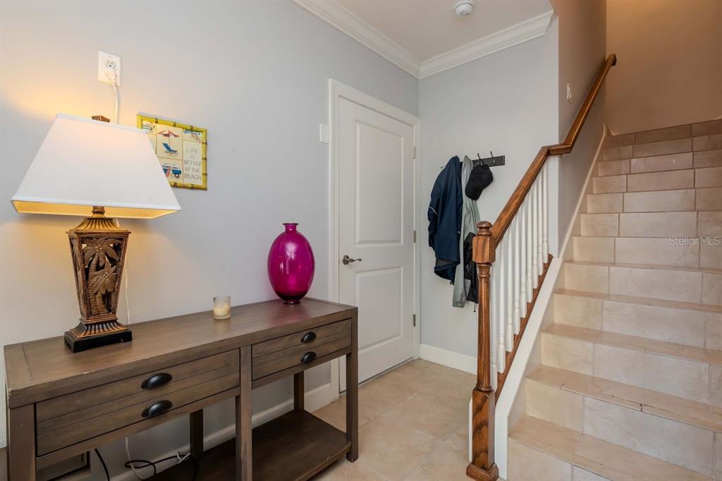 An entryway features a wooden console table, a lamp, a purple vase, and a staircase — 196 HAVEN BEACH DRIVE, INDIAN ROCKS BEACH, FL