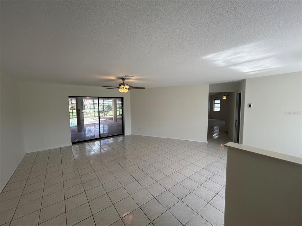 A spacious living room features light-colored tile flooring, a ceiling fan, and sliding glass doors — 2093 RIO DE JANEIRO AVENUE, PUNTA GORDA, FL