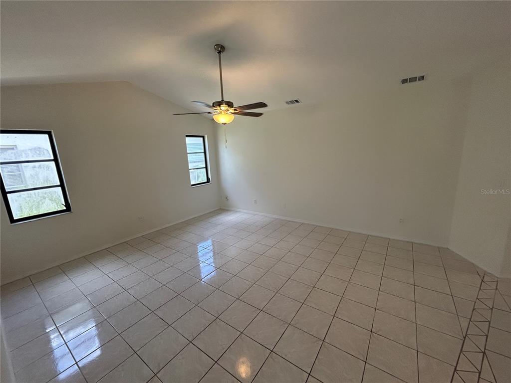 An empty room features light-colored floor tiles, white walls, and a ceiling fan — 2093 RIO DE JANEIRO AVENUE, PUNTA GORDA, FL