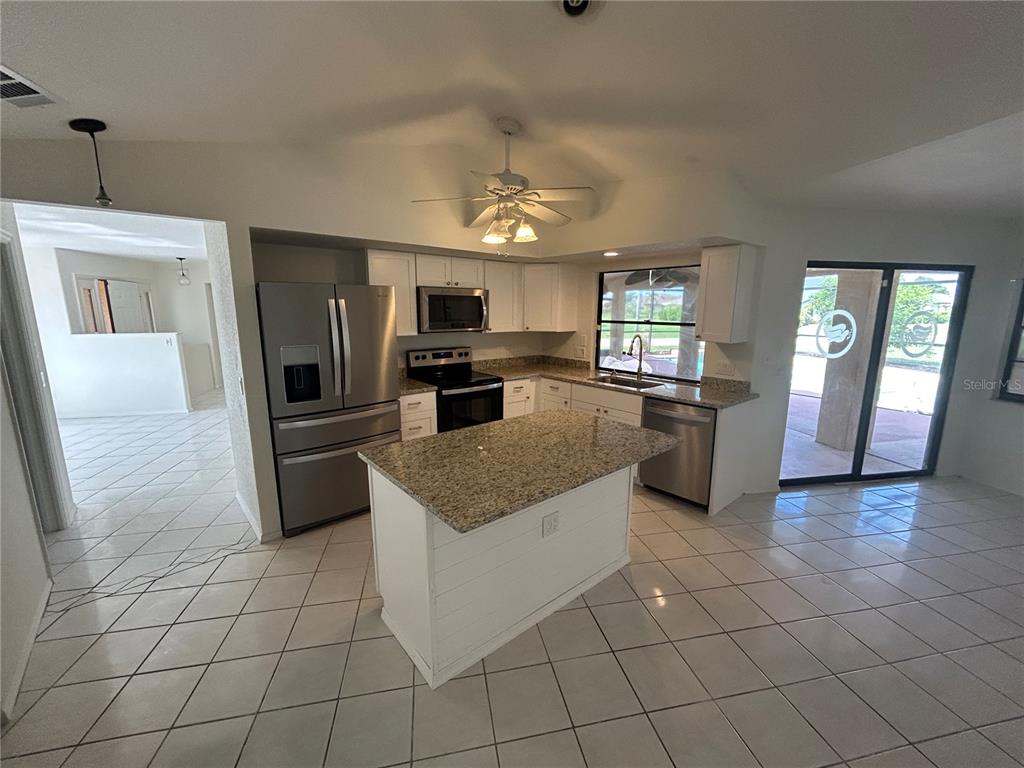 A kitchen features white cabinets, granite countertops, stainless steel appliances, and a central island — 2093 RIO DE JANEIRO AVENUE, PUNTA GORDA, FL