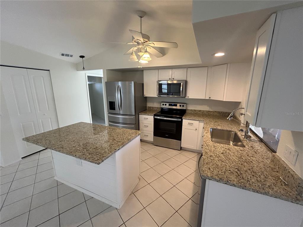 A kitchen features white cabinets, granite countertops, stainless steel appliances, and a central island — 2093 RIO DE JANEIRO AVENUE, PUNTA GORDA, FL