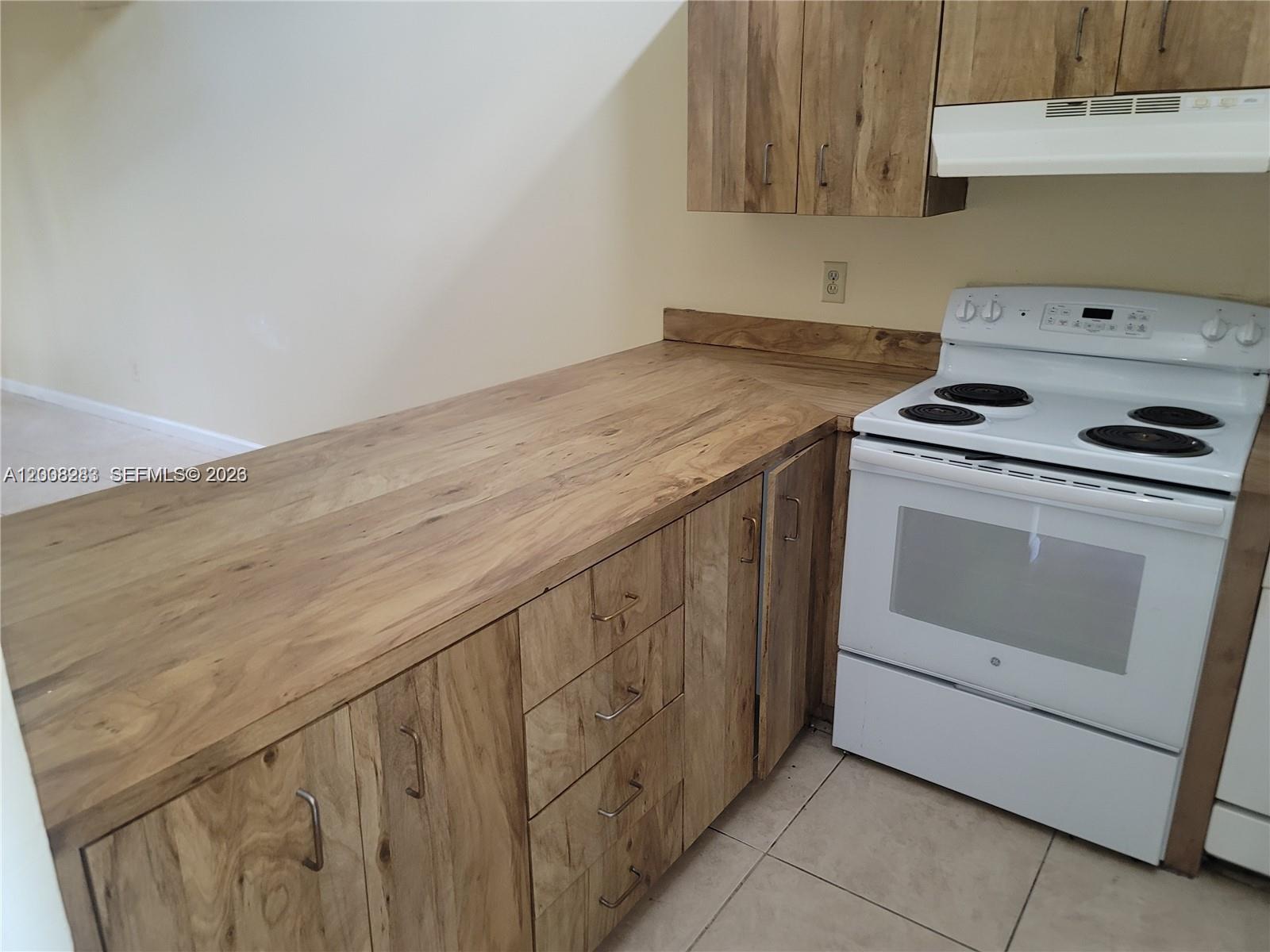 A kitchen features wood-grain cabinets, a long countertop, and a white electric range — 6948 SW 36th Ct # Z, Miramar FL 33023, MIRAMAR, FL